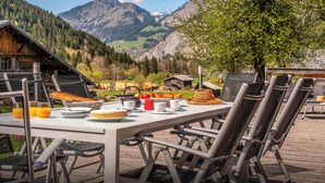 An outdoor dining area with a table set for two, chairs, and a mountain view in the background.