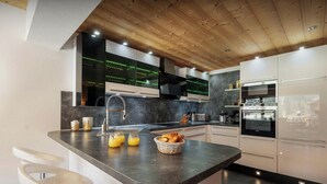 A modern kitchen with a wooden ceiling, built-in appliances, and a breakfast bar.