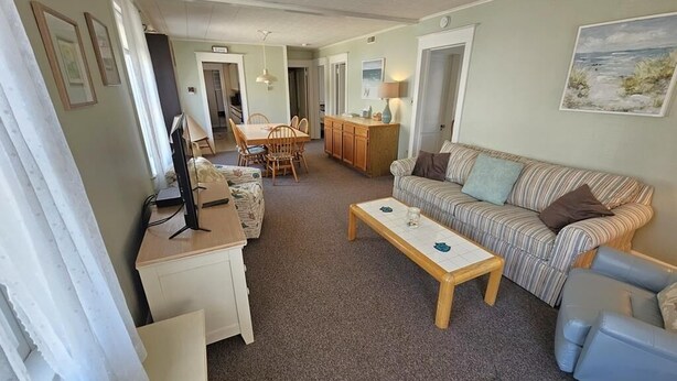 A living room with a sofa, a coffee table, a dining table with chairs, and a kitchen area. - Bright & Welcoming 2BR Near Beach, Boardwalk & Local Attractions (Ocean City)