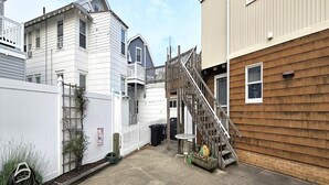 A residential area with a wooden staircase leading to a garage, a white fence, and a small garden area. - Bright & Welcoming 2BR Near Beach, Boardwalk & Local Attractions (Ocean City)