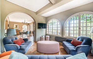 Ein großzügiger Wohnbereich mit zwei Sofas, einem runden Hocker und einem Esstisch.