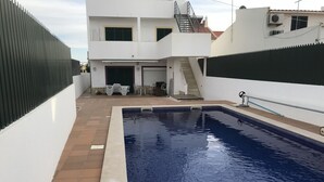 A swimming pool with a white building in the background. - Altura verde apartment (Altura)