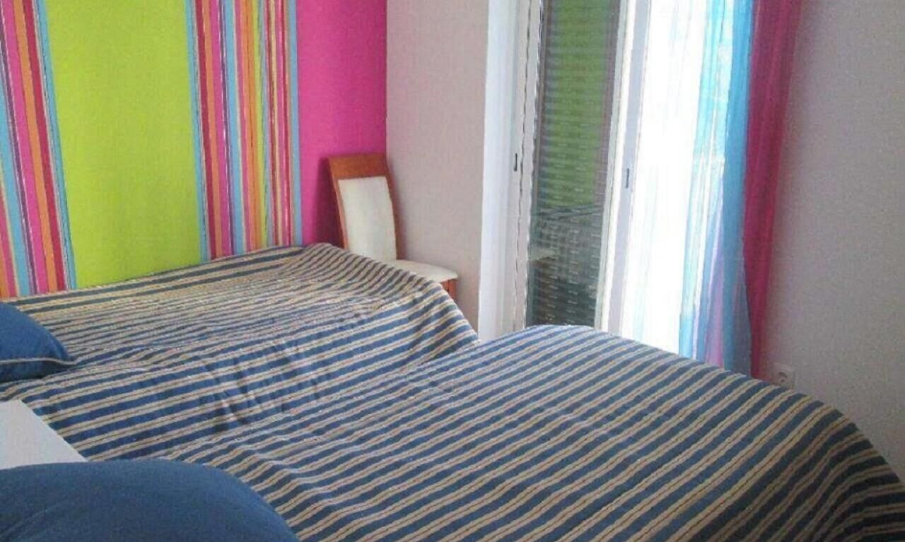 Een kamer met een bed, een stoel en een raam met gordijnen.