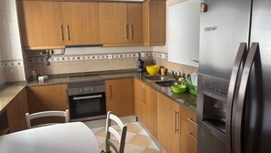 A kitchen with wooden cabinets, a stainless steel refrigerator, a stove, and a sink. - Altura verde apartment (Altura)
