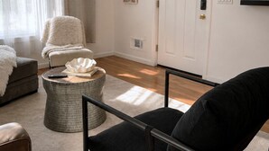 A living room with a sofa, armchair, ottoman, and a TV on the wall. - Massive 4-bedroom, 3-bathroom duplex apt with garage parking in Jersey City (Jersey City)
