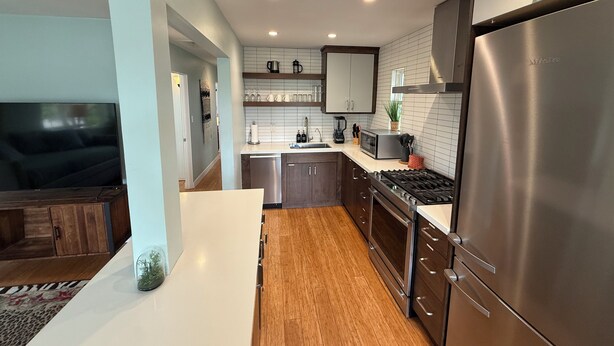 A modern kitchen with stainless steel appliances, wooden cabinets, and a white countertop. - Hot Tub. A/C. Laundry. 2 Parking Spots. Orchard. (San Diego)