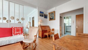 En hyggelig stue med et træbord, en sofa med rød pude og en stol med hvid pude.