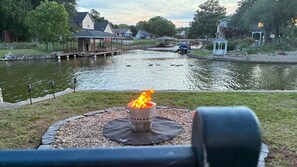 Vista sobre un lago con una chimenea exterior, un muelle y edificios residenciales.