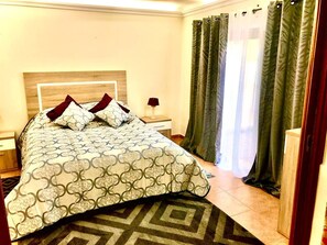 Ein Hotelzimmer mit Bett, Nachttisch, Lampe und Vorhängen.