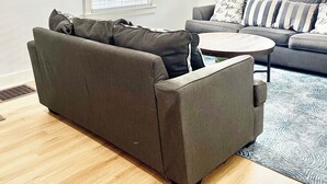 A living room with a grey sofa, a coffee table, and a patterned rug. There are two windows with blinds, and framed pictures on the walls. - Louisville Home by Kentucky Exposition Center & Churchill Downs (Louisville)