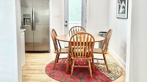 A dining area with a wooden table and chairs, a red patterned rug, a stainless steel refrigerator, and a white door with a window. - Louisville Home by Kentucky Exposition Center & Churchill Downs (Louisville)