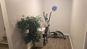 Een hal met een potplant, een vastzittende hometrainer en een motiverende poster.