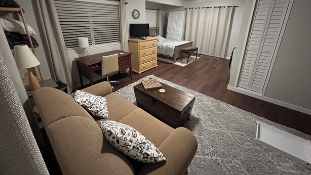 Ein Wohnzimmer mit Sofa, Couchtisch, Fernseher, Schreibtisch und Bett.