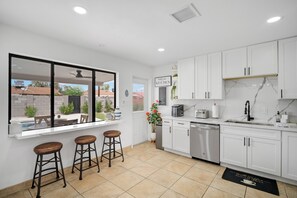 A modern kitchen with white cabinets, a large window, and a bar stool area. - Marvelous 4-bedroom house with AC in sunny Phoenix (Phoenix)