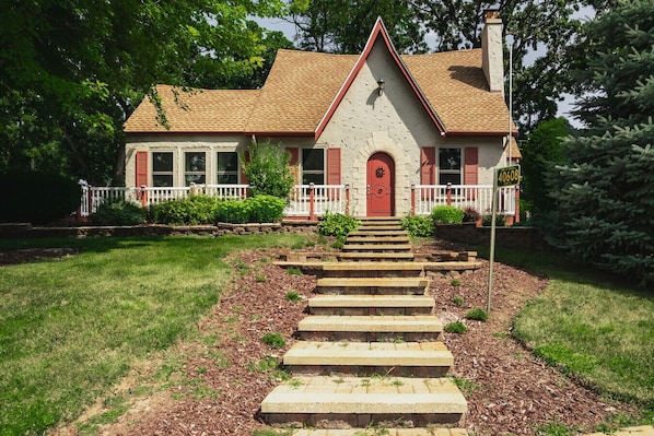 A house with a red door, a white picket fence, and a stone staircase leading to the front.