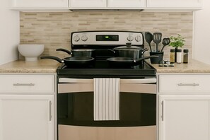 A kitchen with a stove, pots, a white bowl, and a plant. - Kingbed W/pool/gym/bbq@theheights,longstaydiscount (Houston)