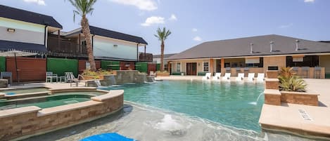 A swimming pool with multiple levels and a lounge area with chairs.