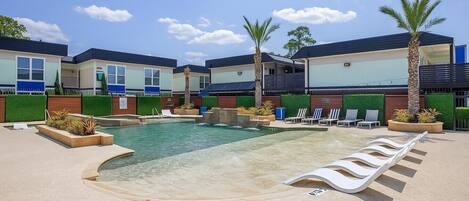 A modern hotel with a pool area, including lounge chairs and palm trees.