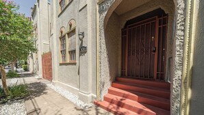A building with a stone facade, a red door, and a staircase leading to the entrance.