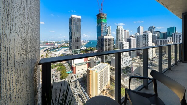Um edifício alto com vista para a paisagem urbana, incluindo um porto de iates e outros edifícios altos.
