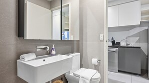Une salle de bain moderne avec un grand lavabo, des toilettes et un miroir au-dessus du lavabo.
