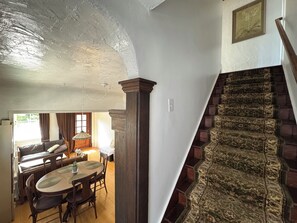 Ein Essbereich mit Holztisch und Stühlen, einer Hängelampe und einer Treppe mit gemustertem Teppich.
