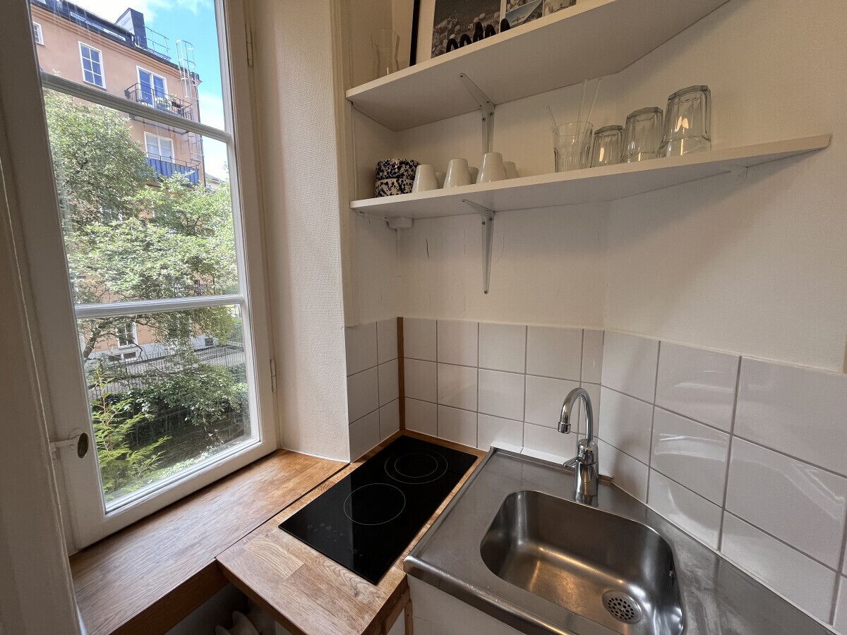 Ett litet kök med ett fönster, en diskho och en spis.