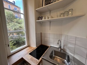 Ett litet kök med ett fönster, en diskho och en spis.