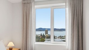 Et hotelværelse med en seng, et natbord med en lampe og et vindue med gardiner.