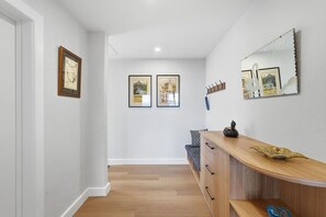 A hallway with a wooden bench, a mirror, and framed pictures on the wall. - Designer Stay w/ River Views (Sandy Bay)