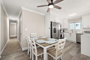 A modern kitchen with white cabinets, a stainless steel refrigerator, and a ceiling fan. - Midtown OC Retreat | Ocean Block | Sleeps 10 (Ocean City)