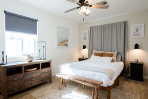 Ein Schlafzimmer mit Bett, Nachttischen, einem Schminktisch, einem Deckenventilator und einem Fenster mit Blick.