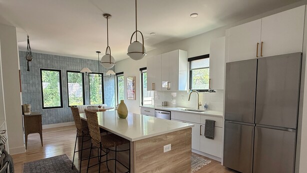 Una cocina moderna con una isla central, electrodomésticos de acero inoxidable y amplios ventanales.
