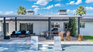 Une maison moderne dotée d’un patio couvert, d’une piscine et d’un espace barbecue.