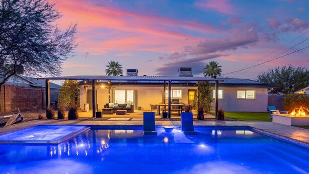 Une maison moderne dotée d’une piscine, d’un espace salon extérieur et d’un patio.