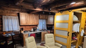 A cozy log cabin interior with a dining area, kitchen, and a massage chair.
