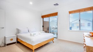 A bedroom with a bed, bedside table, and a view of the outside.