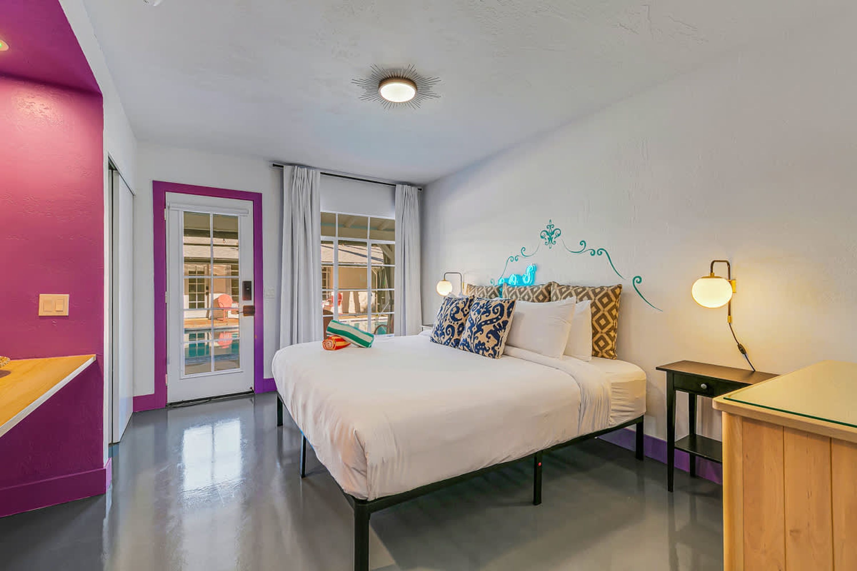 Een slaapkamer met een bed, nachtkastjes, een bureau en een raam met gordijnen.