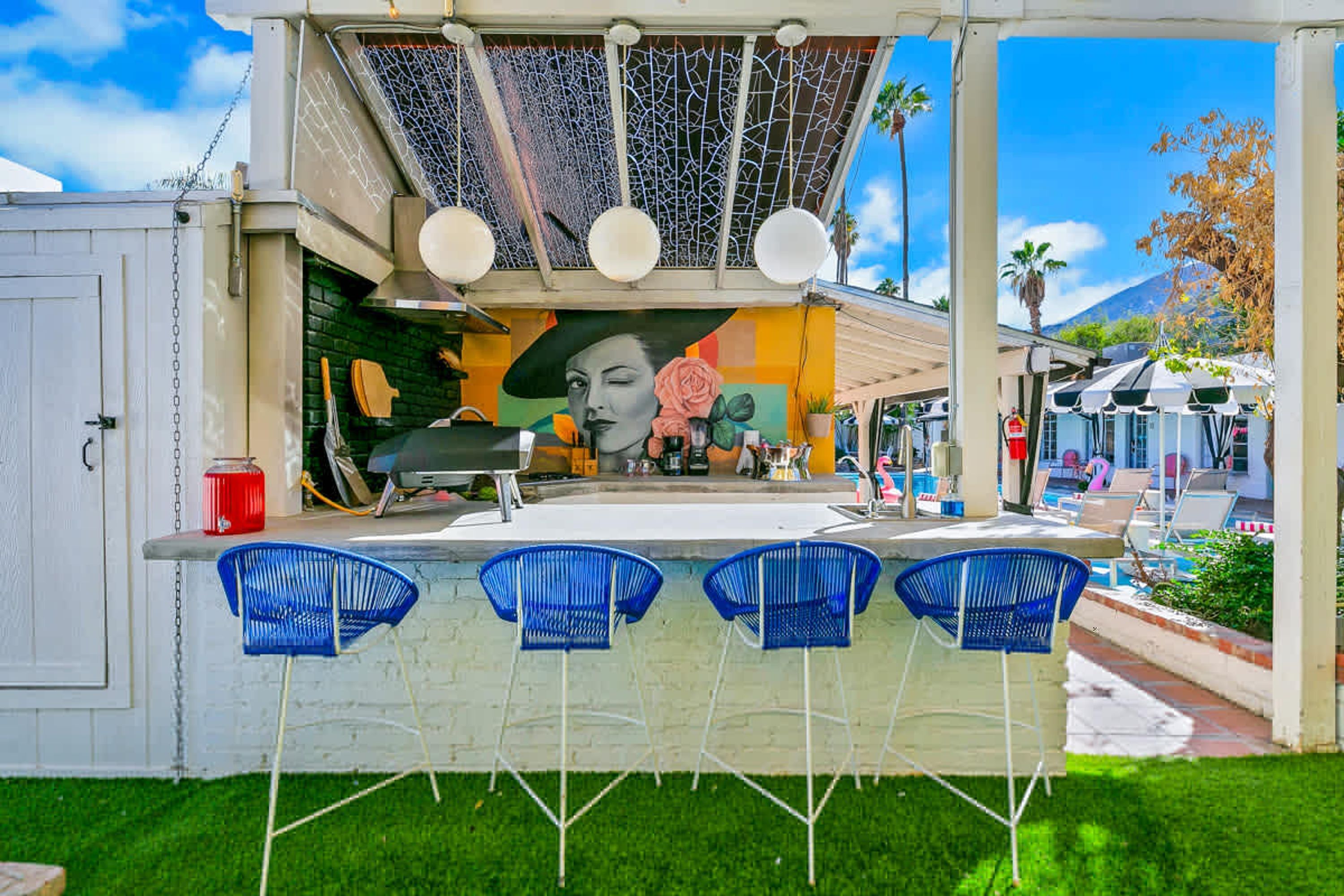 A bar area with a mural, outdoor seating, and a poolside view.