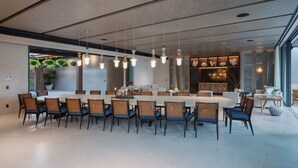 A modern dining area with a long table, chairs, pendant lights, and a view of the outdoors. - Casa De Elementos in Punta Mita (Punta de Mita)