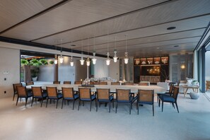 A modern dining area with a long table, chairs, pendant lights, and a view of the outdoors. - Casa De Elementos in Punta Mita (Punta de Mita)