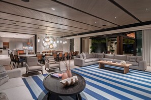A modern living room with a large sofa, a coffee table, and a dining area with chairs and a table. - Casa De Elementos in Punta Mita (Punta de Mita)