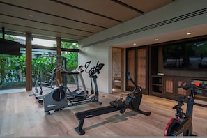A gym with cardio machines, a rowing machine, and a TV screen. - Casa De Elementos in Punta Mita (Punta de Mita)