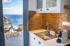 Una cocina con vistas al océano, un lavamanos, armarios y una cafetera.