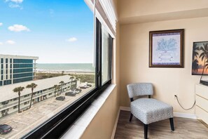 Ein Zimmer mit großem Fenster und Meerblick, einem Sessel und einem Bild an der Wand.