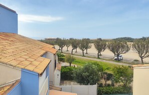 A residential area with a tiled roof, a pathway lined with trees, and a parked car. - Gorgeous apartment in Narbonne with house sea view (Narbonne)