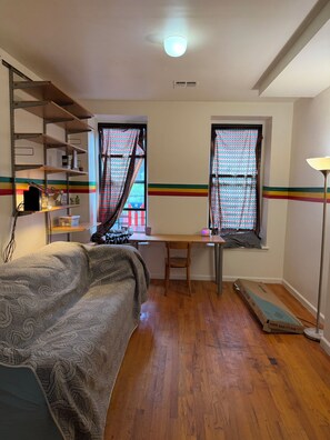A room with a bed, desk, chair, shelves, windows with patterned curtains, and a floor lamp. - 1-Bedroom in perfect NYC Historic Harlem with AC free WiFi (New York)