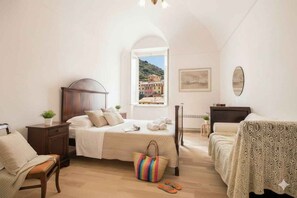 Ein Schlafzimmer mit Bett, Nachttisch, Sessel, Fenster mit Aussicht und ein Beistelltisch.