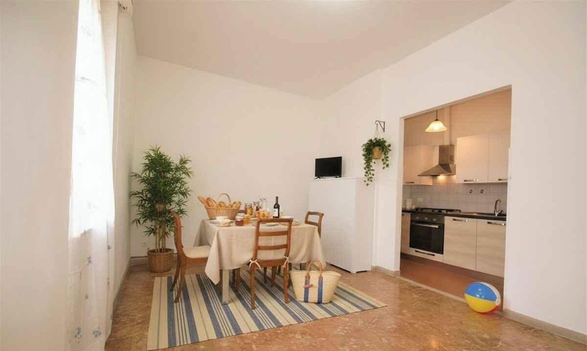 A dining area with a table set for four, a potted plant, and a striped rug.