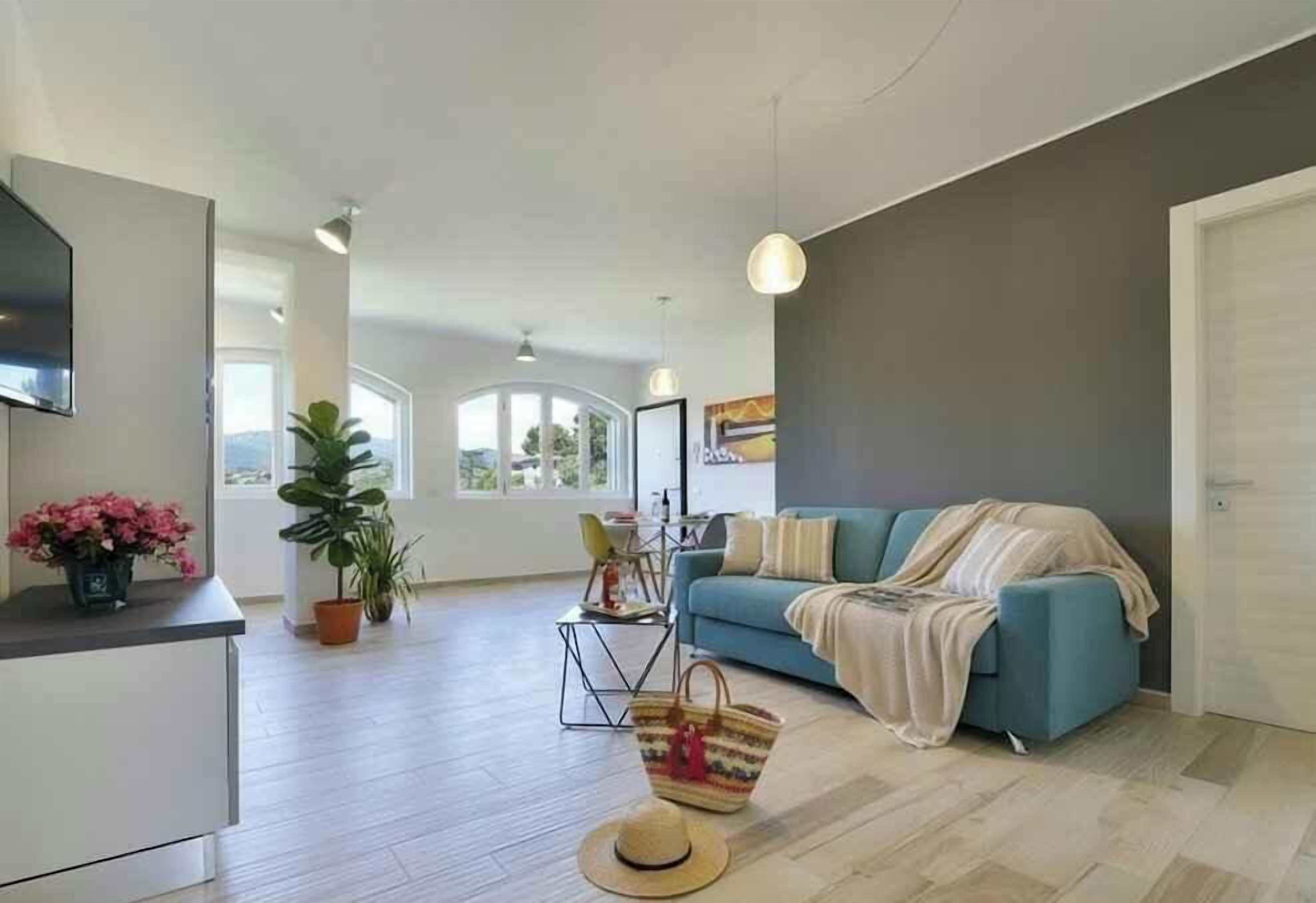 A modern living room with a sofa, a TV, a dining area, and a large window.